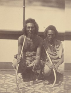 Portrait of Two Native Men Sitting on a Boat Holding Long Curved Sticks, 1865. Creator: Théodule Deveria.