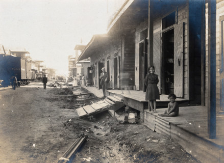 Colón, Panama: unpaved street lined with wooden houses; two children watch from a porch..., 1906. Creator: Unknown.