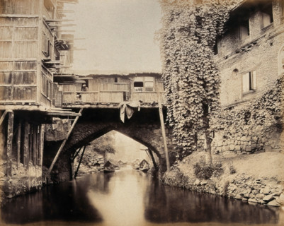 Kashmir: a built-over bridge on a canal betweeen houses, c1870s. Creator: Samuel Bourne.