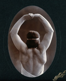A young woman posing semi-naked, back view, with her arms in the air, in a photographic..., c1903. Creator: Unknown.