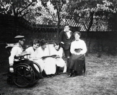 A physically disabled boy sitting in a wheelchair in a garden,  c1910/1925. Creator: Unknown.