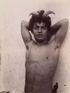 A Sicilian boy naked from the waist up, his hands behind his head, wearing horns, 3 Feb 1899. Creator: Count Wilhelm von Gloeden.