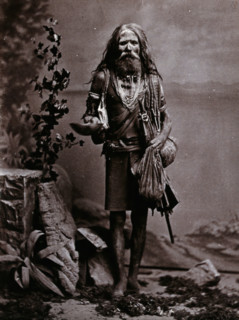 An Indian man wearing many beads, and carrying a begging bowl and an umbrella, in a..., c1900. Creator: Unknown.