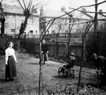 A physically disabled boy sitting in a wheelchair in the back garden of a semi..., c1910/1925. Creator: Unknown.