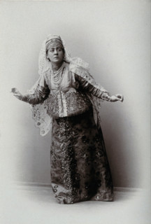 A woman posing in a photographic studio, wearing an embriodered dress, c1900s. Creator: Unknown.
