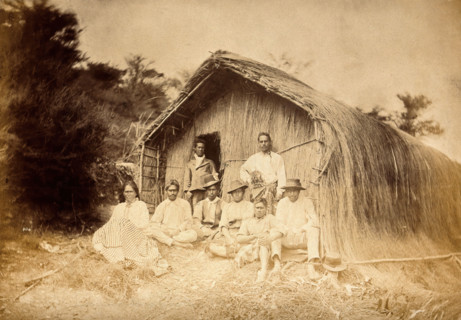 New Zealand: a group of Maori sitting in front of a traditional house, between 1800 and 1899. Creator: Unknown.