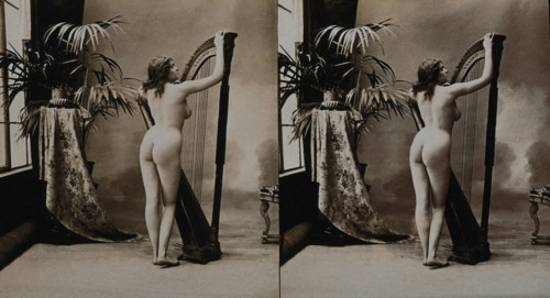 A young woman posing naked in a photographic studio, standing with her back to the camera..., c1900. Creator: Unknown.