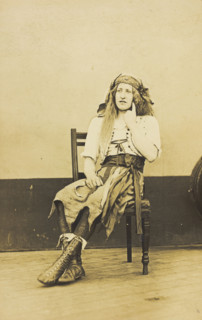 A man in drag sits pensively on a chair, on the deck of a ship, (between 1910 and 1919?). Creator: Unknown.