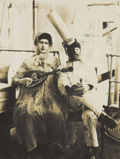 Two sailors (?) on board ship: one in drag is playing a guitar, 1907. Creator: Unknown.