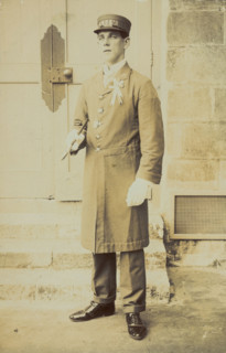 A man dressed wearing a long coat and a hat bearing the word "Cook"...(1910-1919?). Creator: Unknown.