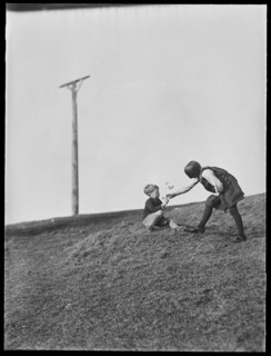 Two children playing in front of Combe Gibbet, Inkpen Hill, Inkpen, West Berkshire, 1925-1935. Creator: George R Long.