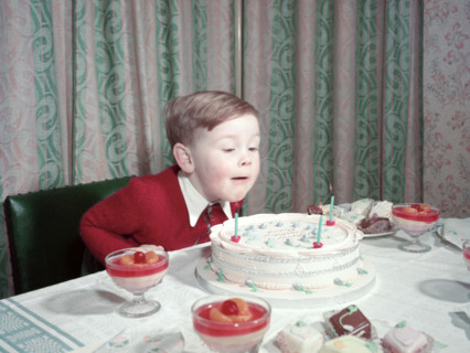 Birthday boy blowing out the candles on his cake, c1955.  Creator: Arthur Charles Kirby Ware.