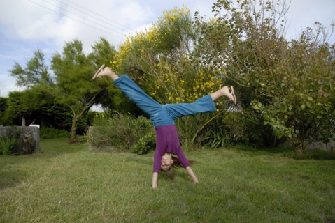 Petite fille faisant la roue dans un jardin