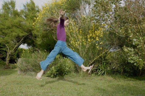 Petite fille faisant un grand saut dans un jardin
