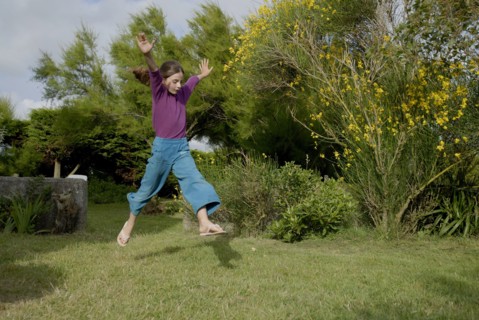 Petite fille faisant un grand saut dans un jardin