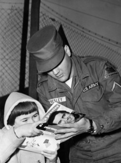 Elvis PRESLEY gives an autograph to a child in 1959