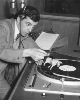 Chris HOWLAND plays records during radio broadcast, 1956