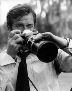 Roger MOORE taking photos with a Pentax SLR camera