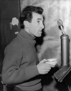 Charles AZNAVOUR with cup in front of microphone and music stand, ca. 1950s