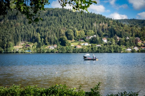 Man in fishing boat on a peaceful Lac de GÃ©rardmer, France, Europe