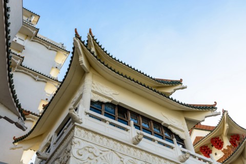 View of the chinese-inspired architecture of the Huatian Chinagora hotel complex with curved roof corners and traditional glazed roof tiles.