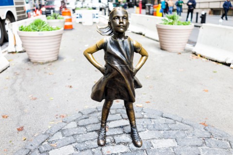 New York City, USA - October 30, 2017: Wall Street stock exchange The Fearless Girl statue facing Charging Bull metal in NYC Manhattan lower financial