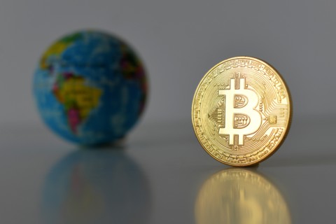 Bitcoin concept. World economy concept. New world currency. Golden coin bitcoin and globe.