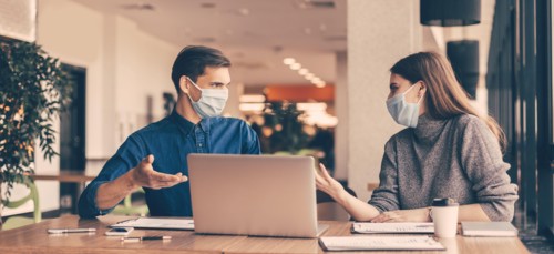 business colleagues in protective masks sitting at the office Desk.