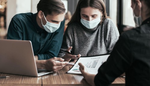 business colleagues in protective masks sitting at the office Desk.