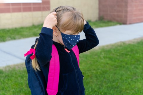 Young student caucasian girl wearing protective cotton mask for school. Return back to school, reopening, new life.