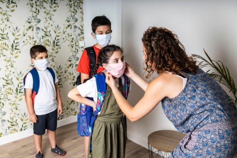 Mother putting face masks on her children before they go to school