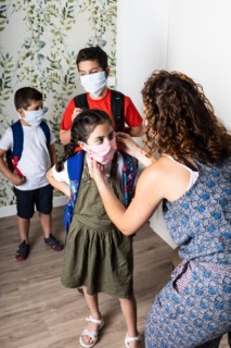 Mother putting face masks on her children before they go to school
