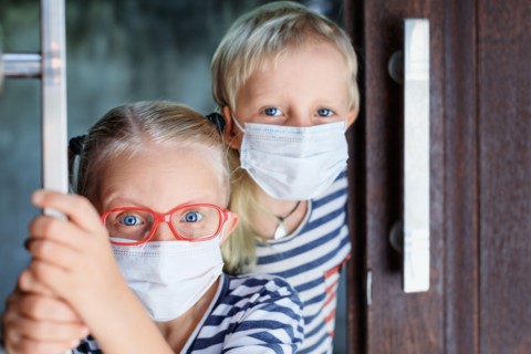 Little children looking unhappy and depressed after staying at home due banned street activity. Kids wearing medical face masks go out for  walk