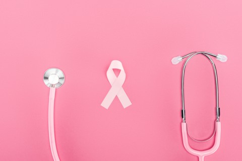 top view of stethoscope and pink breast cancer symbol on pink background