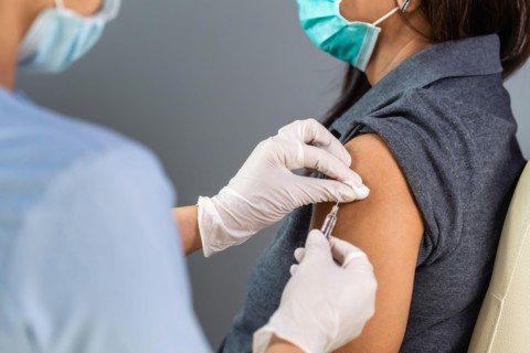 close up doctor holding syringe and using cotton before make injection to patient in medical mask. Covid-19 or coronavirus vaccine