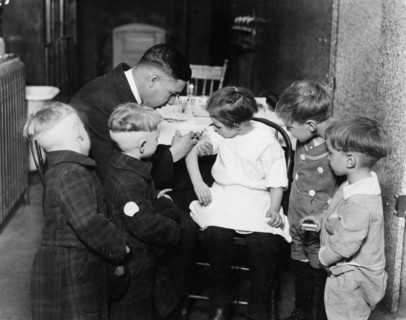 Pediatrician immunizing a little girl while other children are watching