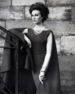 A new line for cocktail and short evening dresses comes from Pierre Cardin. A slim straight sleeveless dress in 'Terylene'/worsted crepe has flowing from the shoulders behind, a full length mantle wit...