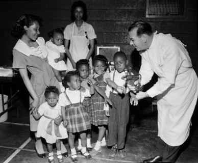 Doctor with a newly-developed jet injector gun prepares to inoculate children on Chicago’s South Side, ca. 1960.