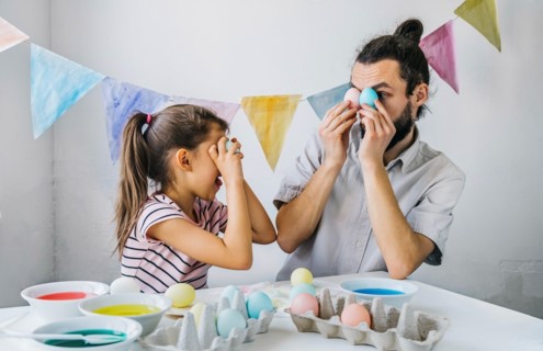 Happy family preparing to Easter celebrate at home. Adorable little girl and her having fun while while dyed easter eggs.