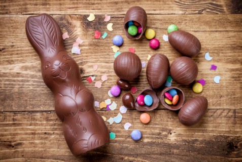 Delicious chocolate easter eggs and sweets on wooden background