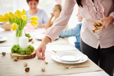 Woman and family preparing place settings at easter dining table