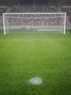 Shallow depth of field (selective focus) image with the penalty kick point on an empty soccer stadium.