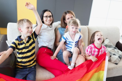 Lgbt family two women with joyful children hold flag