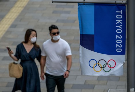 Tokyo, Japan. 09 May, 2021. A couple walks by a Tokyo 2020 flag ahead of the protest against the Tokyo Olympics in front of the New National Stadium, the main stadium for the Tokyo Olympics. Credit: A...