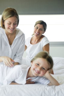 Girl relaxing on bed with her mother and grandmother