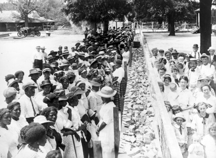 Entitled: "F.M. Gay's annual barbecue given on his plantation every year" shows crowds of African-American and white people separated by a long counter covered with slices of bread at a barbecue in Al...