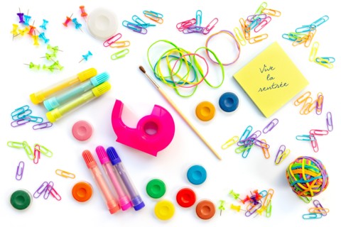 Vive la rentree (meaning back to school in French) written on sticky notes among  colorful school supplies  isolated on white background.