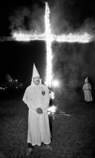 A Member of the KKK stands next to cross lighting in Rumford Me during rally in the small town Maine town. The Klan had been active in Maine in the 1920's and 30's , This group of Klansmen openly invi...