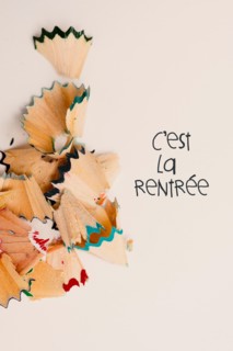 some fan-shaped shavings from pencil crayons of different colors and the text cest la rentree, back to school written in french, on a pale pink backgr