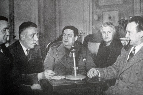 Black and white photograph of Darius Milhaud (1892-1974), French composer, at an evening party with French pianist and teacher Marguerite Long (1874-1966), French composer and pianist Francis Poulenc ...